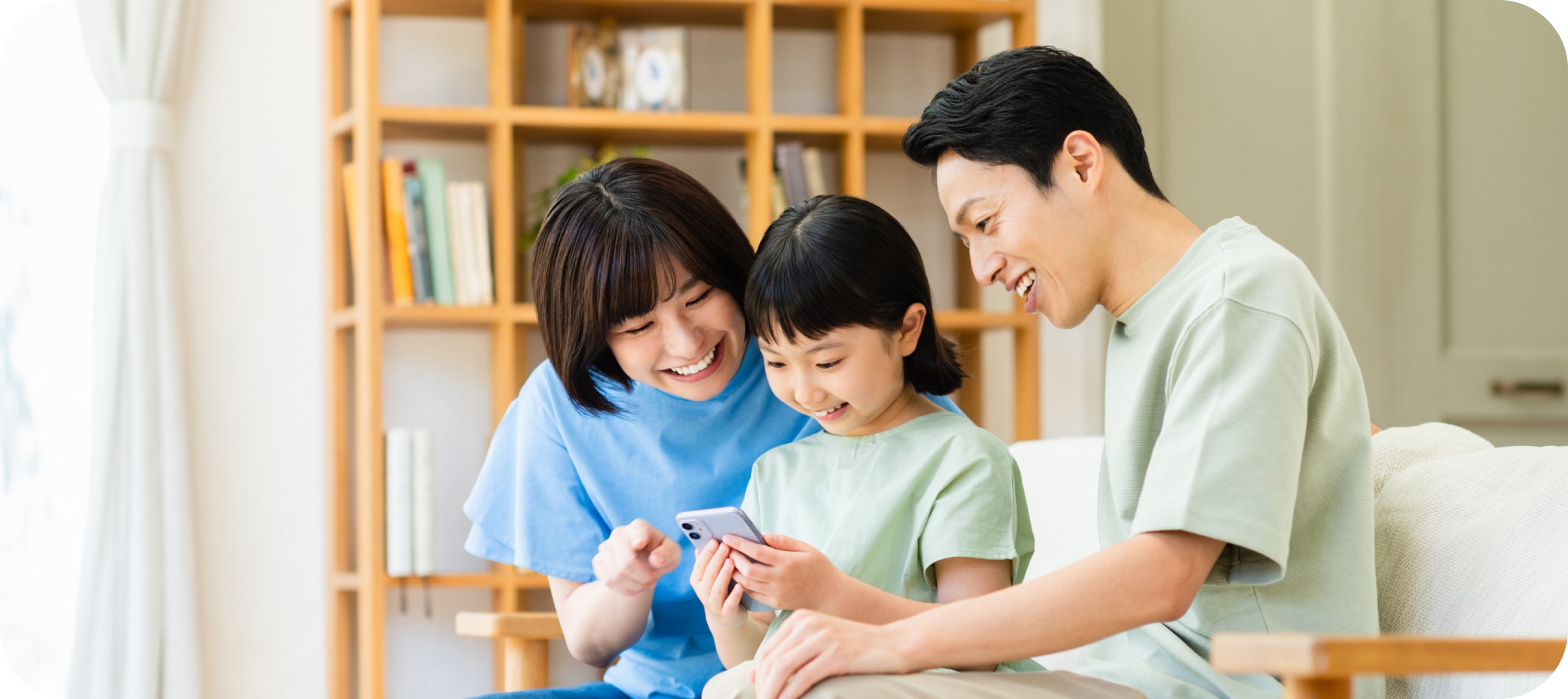 夫婦が笑顔で娘と一緒に娘のスマホを見ている